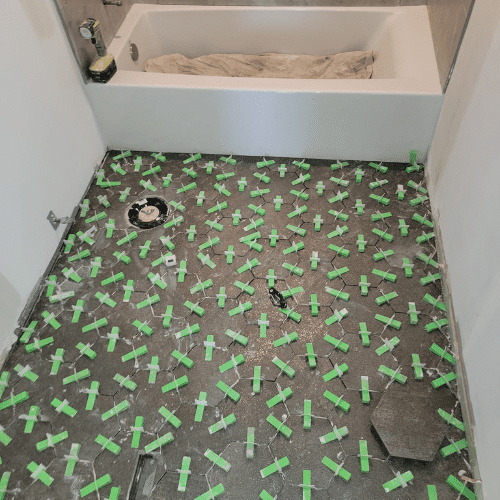 Bathroom remodel featuring patterned tile floor installation in progress by Homes by Covenant