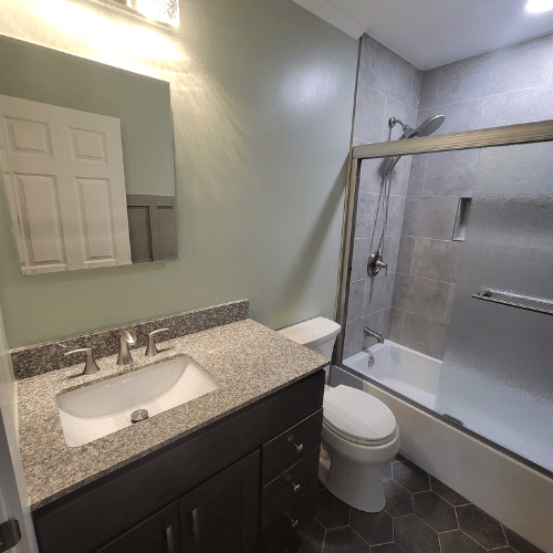 Renovated bathroom with new vanity, lighting, and shower installation completed by Homes by Covenant