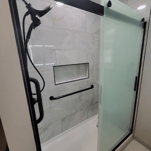 Completed bathroom shower renovation featuring modern tile and sliding glass door by Homes by Covenant