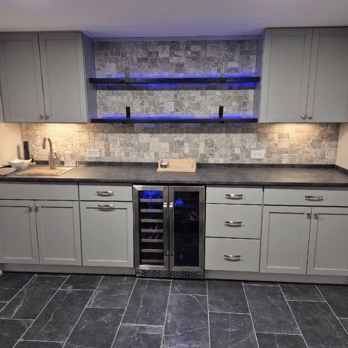 Modern basement kitchenette with backsplash lighting and cabinetry designed by Homes by Covenant