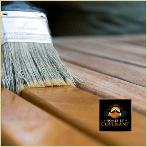 Brush applying wood stain to porch flooring during refinishing.