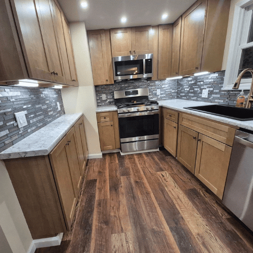 Completed kitchen renovation by Homes by Covenant featuring maple cabinetry, stainless-steel appliances, marble-look countertops, tile backsplash, and recessed lighting.